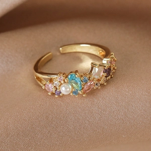 Macro detail of golden heart ring featuring multi-color zircons and a central pearl accent