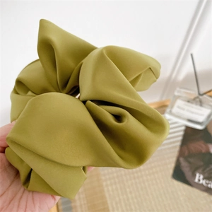 Detailed close-up of a large mustard green matte satin scrunchie with soft fabric texture