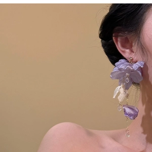 Dettaglio di lunghi orecchini a petalo con fiori in seta viola e nappe di cristallo a goccia