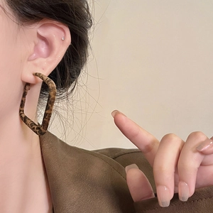 Close-up of model wearing geometric square leopard print earrings in a soft fabric finish