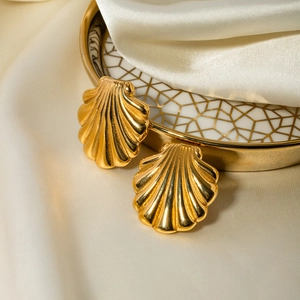 Detailed view of fan-shaped shell earrings in 18k gold finish on silk and grid tray