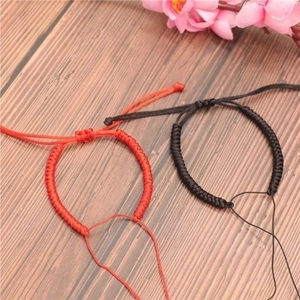 Handmade red and black braided rope bracelets for couples on natural wood background