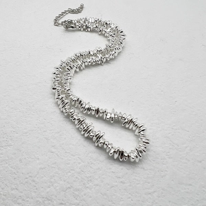 Detailed macro view of irregular flat silver beads with lobster clasp and extension chain
