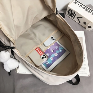 Zaino da viaggio beige minimalista con scomparto per tablet e ciondolo in peluche