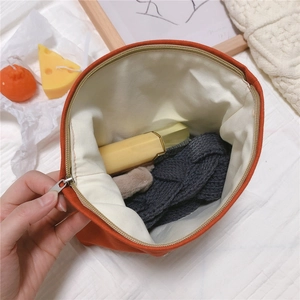 Detail view of orange houndstooth canvas pouch showing spacious interior with lipstick