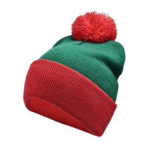 Detailed knit texture of a red and green Christmas elf beanie with a fluffy pom-pom
