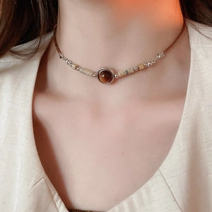 Close-up of vintage ethnic necklace with round stone pendant on model's neckline