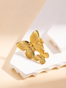 Close-up of golden twin butterfly ring with detailed wing texture on white stone surface
