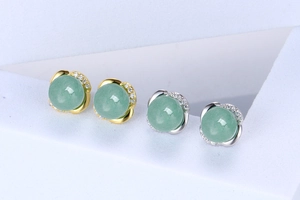 Detailed macro view of jade stud earrings with gold and silver crystal bases