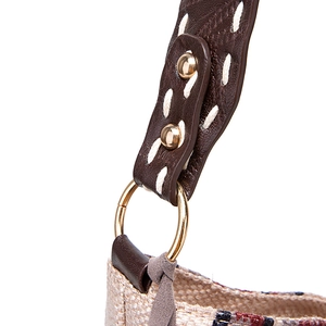 Detail of bohemian woven bag with brown leather strap and contrast white stitching