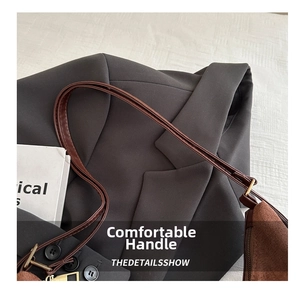 Detail of brown suede tote bag with dark leather straps on a grey blazer jacket