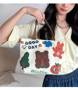 Lifestyle view of canvas tote bag with cartoon bear print and brown top handles