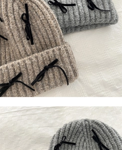 Detail showing soft knitted texture and black velvet bow decorations on the beanie hat