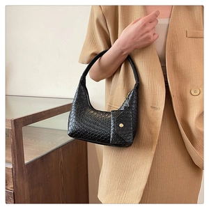 Detail of black woven shoulder bag featuring golden zippers and a small front pouch pocket