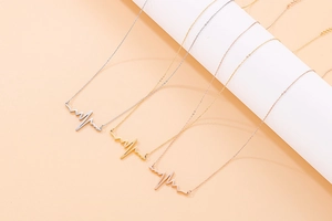 Detailed view of heartbeat pulse necklaces in silver, gold, and rose gold finishes