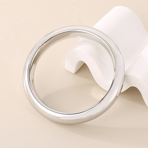 Detailed view of wide 13mm silver stainless steel bangle on white geometric stand