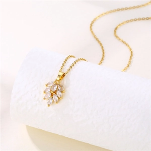 Detail shot of golden leaf pendant with marquise-cut zircons on a white display stand