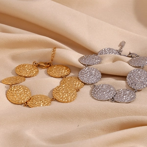 Dettaglio dei dischi rotondi martellati in oro e argento su un bracciale regolabile chic