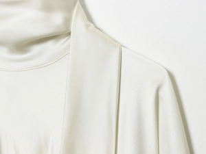 Detailed macro view of white satin dress showing smooth neck tailoring and silk texture
