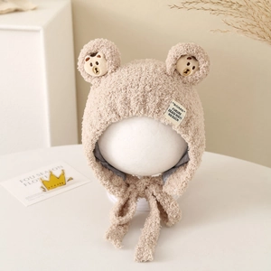Close-up of soft beige fleece lining and embroidered bear details on infant earflap hat
