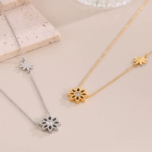 Close-up of gold and silver daisy necklaces with clear gemstones on stone prop