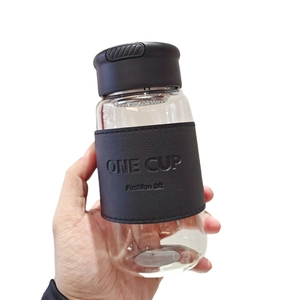 Minimalist glass water bottle with black leather sleeve and carry strap, white background