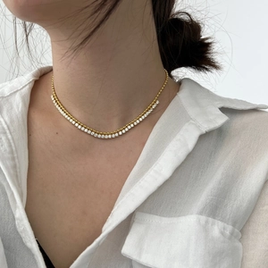 Double layer gold necklace with beaded chain and cubic zirconia tennis strand on neck