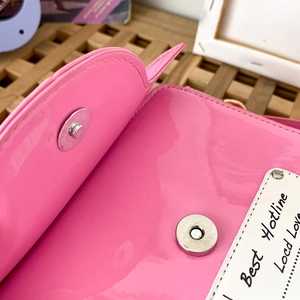 Detail of pink patent leather bag showing magnetic closure and Best Hotline decorative tag