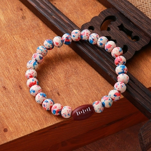 Detail of beaded bracelet with turquoise patterns and a miniature brown rugby ball bead