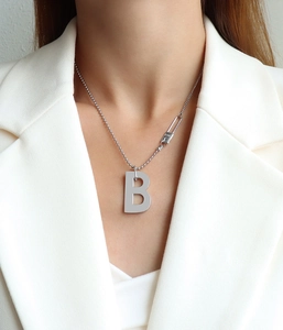 Détail du collier argenté avec pendentif lettre B, chaîne asymétrique et boucle gravée