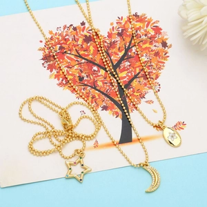 Detailed view of three gold bead chain necklaces with star, moon and floral pendants