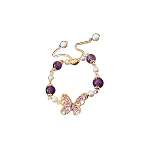 Golden butterfly bracelet with purple amethyst and pearls on a clean white background