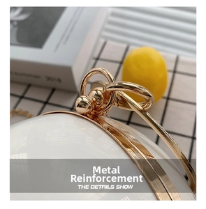 Detail of reinforced gold metal hardware on a white spherical evening bag handle