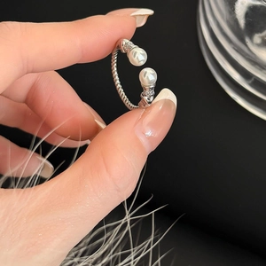 Detailed view of silver open ring with dual pearls and sparkling zircon accents
