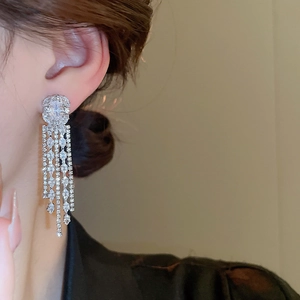 Detail showing elegant silver tassel earrings with white zircon on a female model