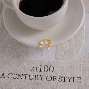 Detail of adjustable gold ring with three sparkling zircons on a white saucer edge