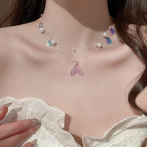 Detailed close-up of double-layer necklace with shell pieces and a pink mermaid tail pendant