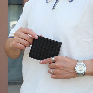 Close-up of hand holding a brown woven leather bifold wallet for men with textured finish