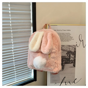 Detailed view of plush pink and white bunny ear backpack hanging against a studio wall