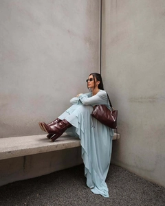 Detail of bohemian light blue ruffle dress paired with brown leather boots and handbag