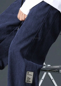 Detail of navy corduroy pants featuring a textured fabric and a leather decorative patch