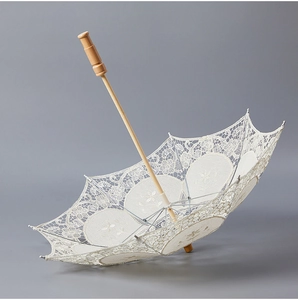 Detailed macro view of vintage bridal lace umbrella with floral embroidery and wooden handle