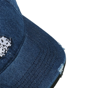 Close-up of distressed denim baseball cap with white embroidery and worn brim details