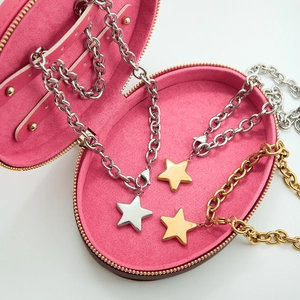 Detailed macro shot of gold and silver star pendant necklaces in a pink velvet jewelry box