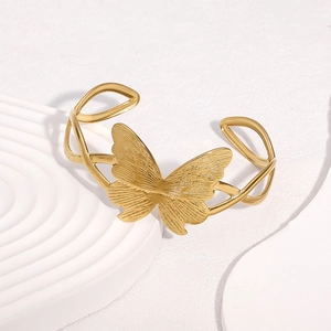 Minimalist 18k gold butterfly open bangle on a modern white display stand