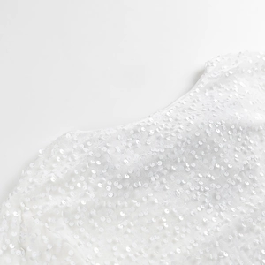 Gros plan détaillé du tissu à paillettes blanches avec broderies et reflets brillants