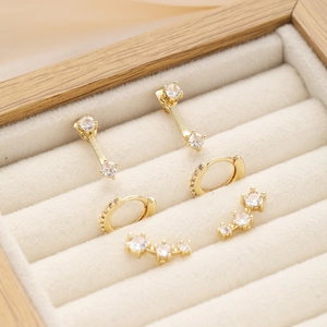 Detailed close-up of golden zircon earring set on a beige velvet display box