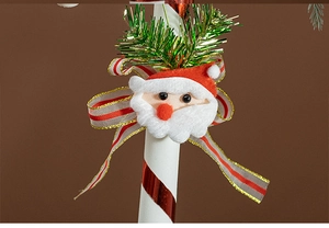 Detail of felt Santa head with red white bow on spiral Christmas candy cane pole