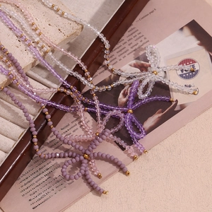 Multi-colored faceted crystal bow necklace and bracelet set with golden beads on vintage book