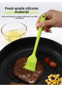 Macro detail of grass green silicone brush spreading oil on steak in a black frying pan